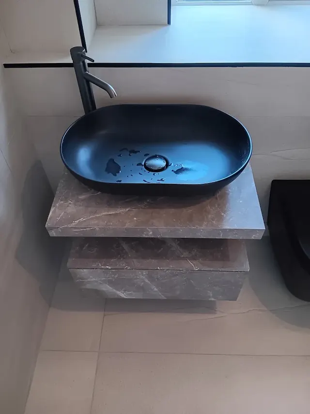 Black countertop basin on a stone-effect vanity