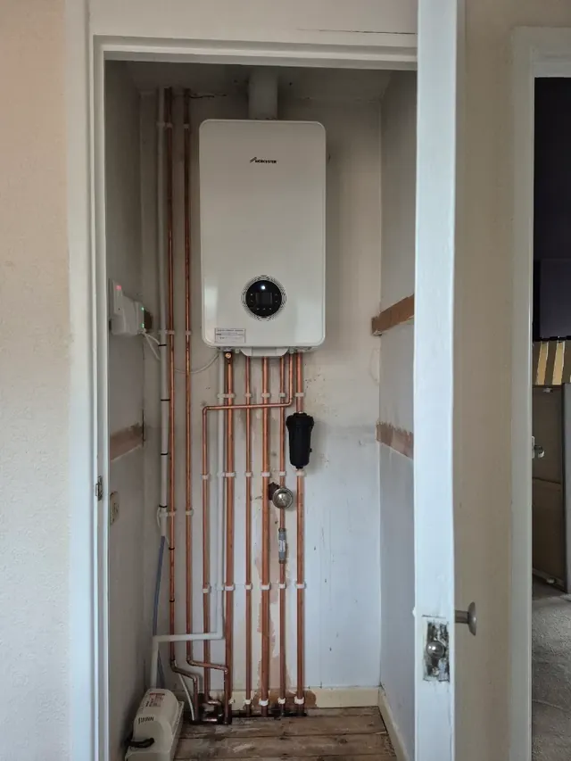 Worcester Bosch boiler in a cupboard, with the pipework run neatly in copper and a magnetic filter fitted